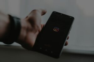 Hand hält Handy, welches Instagram öffnet